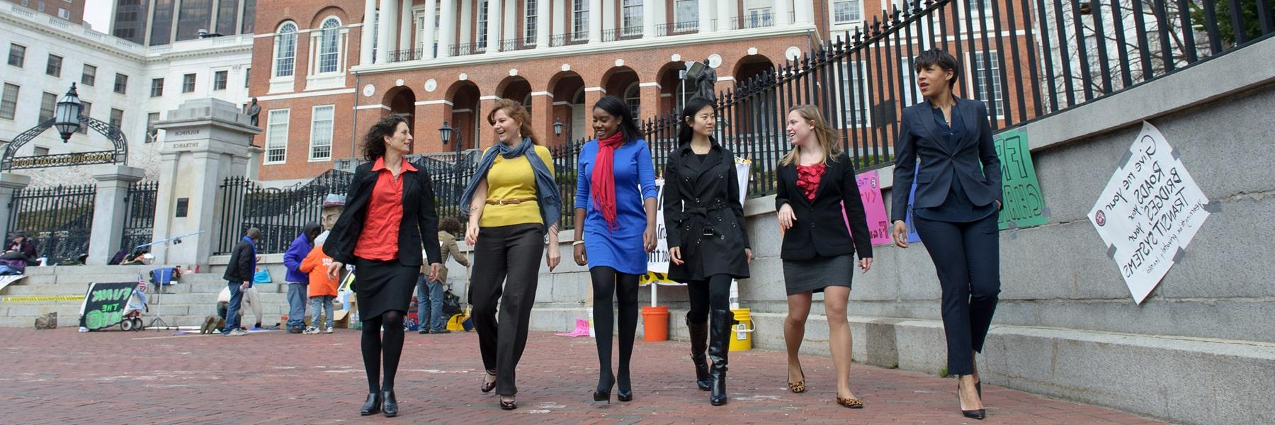 women in casual business attire walking in front of Massachusetts State House